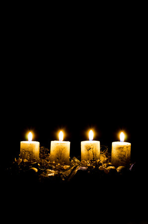 four burning advent candles with decoration and adornments on black background copy spaceの写真素材