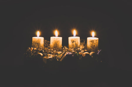 four burning advent candles with decoration and adornments on black backgroundの写真素材