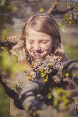 adorable girl with long blond hair in spring park outdoorsの写真素材