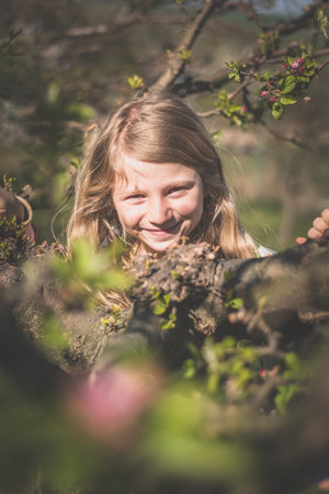 adorable girl with long blond hair in spring park outdoorsの写真素材