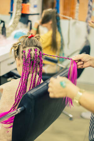 Girl in a barber shop makes her pink afro-pigtailsの写真素材