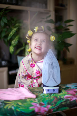 The girl at home irones her clothes and smiles.の写真素材