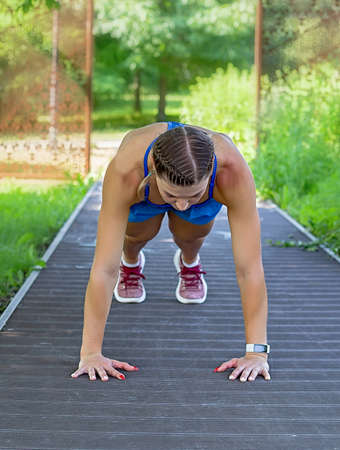 Sports girl makes a plank in the park