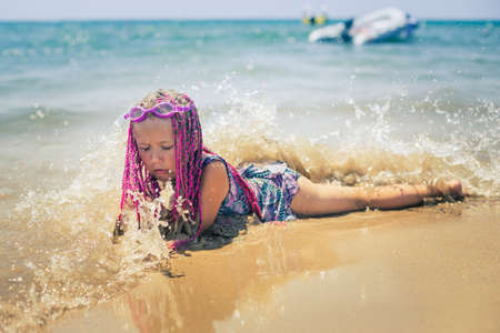 A girl with pink pigtails lies on the beachの写真素材