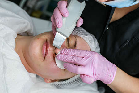 Cosmetologist girl does ultrasonic cleaning of the faceの写真素材
