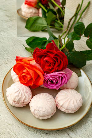 Marshmallow in a gray plate, stylized with fresh roses.の写真素材