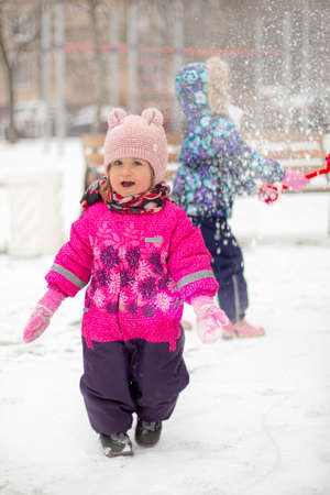 A little girl in a warm rose jumpsuit and a cap with bear ears smiles.の写真素材
