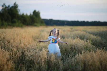A girl with two tails, dressed in football with a unicorn, walks in a wheat field and smiles.の写真素材