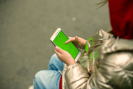 A girl with a phone on the street. Green chromakey screen.の写真素材