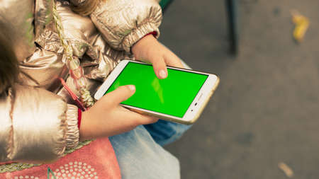 A girl with a phone on the street. Green chromakey screen.の写真素材