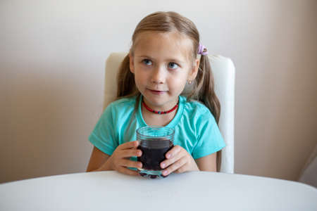 Happy little girl drinking soda from glassの写真素材