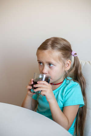 Happy little girl drinking soda from glassの写真素材
