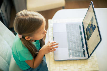 Little cute girl uses laptop to have video callの写真素材