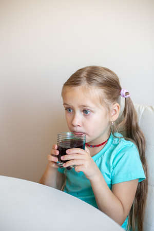 Happy little girl drinking soda from glassの写真素材