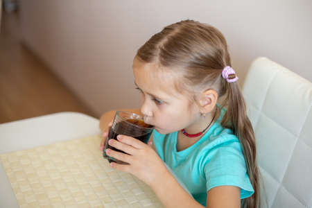 Happy little girl drinking soda from glassの写真素材