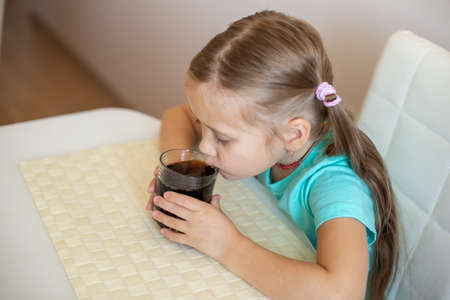 Happy little girl drinking soda from glassの写真素材