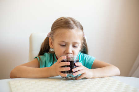 Happy little girl drinking soda from glassの写真素材