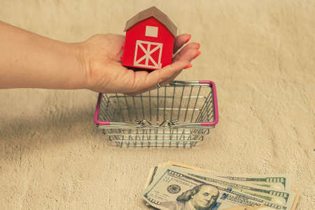Red house with a stack of dollar bills. The concept of buying a house.の写真素材