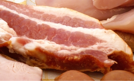 piece of raw bacon surrounded by other meats