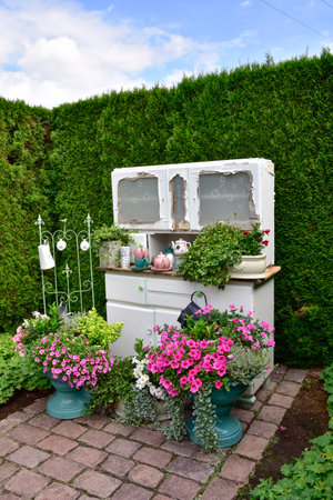 An old sideboard and flower containers as decoration in an English style show garden on a warm summer day.の写真素材