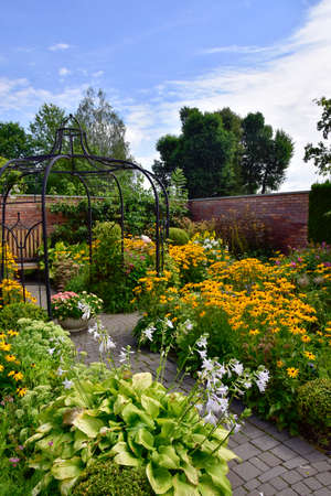 Show garden, an English garden full of summer flowers blooming and green plants, surrounded by a red brick wall on a summer day.の写真素材