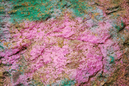 Brown stone painted with paint in pink and green. Rock background, texture.