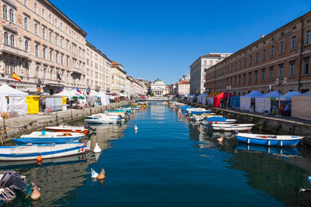 TRIESTE, ITALY - MAY 25, 2014: Buildings reflected in the calm sea water of the Canal Grande in Trieste city, Italy. Church of Saint Antonio on the backgroundのeditorial素材