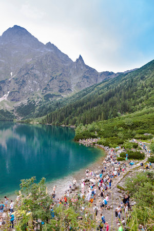 TATRA MOUNTAINS, POLAND - AUGUST 4, 2015: Groups of tourists walking along the shore of Morskie Oko lake in High Tatra Mountains near Zakopane, Poland. It is one of the most popular destinations in the Tatrasのeditorial素材