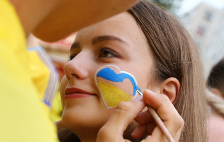 KHARKIV, UKRAINE - SEP. 2, 2017: People draw a heart on cheek during Fan-march of Ukrainian National Football Team supporters on streets of Kharkiv before World Cup 2018 qualif. game Ukraine v Turkeyのeditorial素材