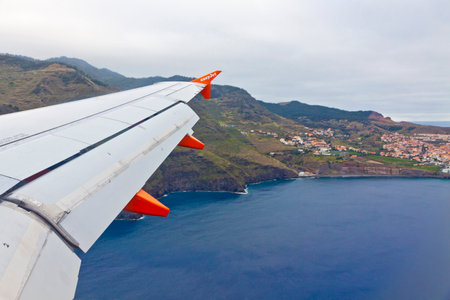 MADEIRA, PORTUGAL - JUNE 14, 2013: Airbus A320 operated by EasyJet (flight number EZY 7603) flights over Madeira island. Aerial view of Atlantic ocean coast through the airplane windowのeditorial素材
