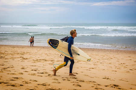 BORDEAUX, FRANCE - JUNE 13, 2017: Unidentified surfer walks on beach of the Atlantic coast of France near Lacanau-Ocean, Bordeaux, Franceのeditorial素材