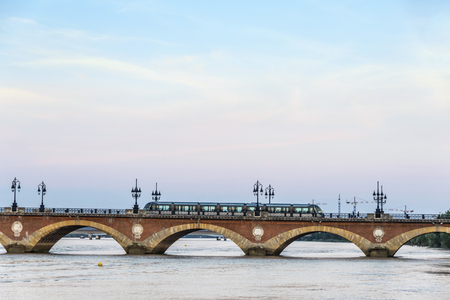 Tram crossing the Pont de Pierre, bridge over the Garonne river in Bordeaux city, Franceの写真素材