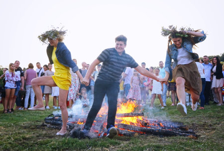 Kyiv, Ukraine - July 6, 2018: Young people jump over the flames of bonfire during the traditional Slavic celebration of Ivana Kupala holiday in Pirogovo open-air ukrainian folk museum in Kyiv, Ukraineのeditorial素材