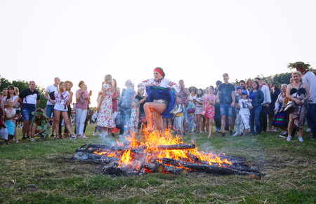 Kyiv, Ukraine - July 6, 2018: Young people jump over the flames of bonfire during the traditional Slavic celebration of Ivana Kupala holiday in Pirogovo open-air ukrainian folk museum in Kyiv, Ukraineのeditorial素材