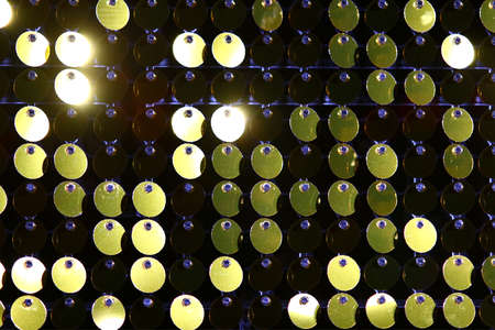 Background sequin. Close-up abstract glitter background with blinking lights. Fashion fabric golden glitter sequins backgroundの写真素材