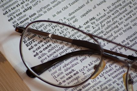 Reading glasses on a dictionary with the word educateの写真素材