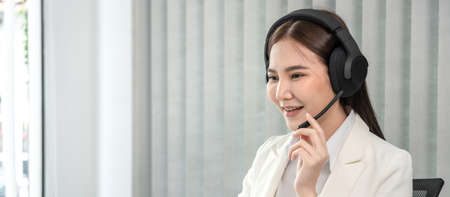 Female call center provides information to a customer calling for help, Contact us, Service with a beautiful and friendly voice, Long distance communication, Talk using headphones or headsets.の写真素材