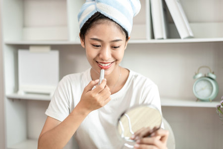 Half Japanese woman putting on makeup and hair to prepare for work in the morning, Facial care and cosmetics, Make up mirror,  Take a shower and put on make-up and get dressed and ready to go to work.の写真素材