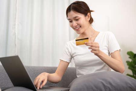 Teenage girl is holding credit card and typing credit card number for payment after shopping online...