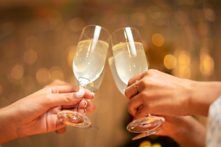 Hands of young people clinking with glass of champagne to celebrate and toasting with happiness in holiday of new year party at home.の写真素材