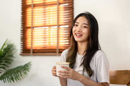 Young woman lesbian looking camera to smiling and enjoying with drinking hot chocolate while spending time to relaxation in living room at home.の写真素材