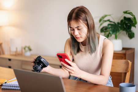 Female fashion artist holding camera and smartphone to checking photo of new fashion collection...