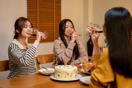 Young smiling woman drinking and clinking glass of wine to toasting with happiness while celebrating in new year party at home.の写真素材