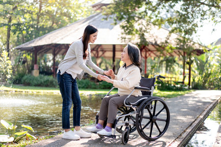 Happy family, Elderly grandmother in wheelchair with daughter smiling enjoying at the garden in the morning.の写真素材
