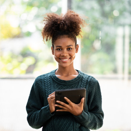 African american student woman in sweater writing information and homework on digital tablet after studying lesson online class for education and knowledge while standing in university.の写真素材
