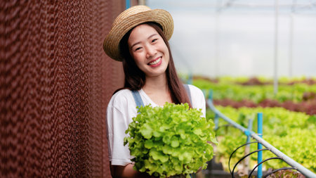 Woman smart farmer working and checking organic hydroponic vegetable quality in greenhouse...