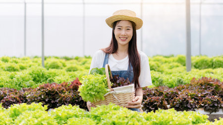Woman smart farmer working and checking organic hydroponic vegetable quality in greenhouse...
