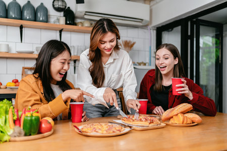 Group of friends drinking beverage and cutting slice of italian pizza for dinner meal while having enjoying with party to celebration for weekend in the kitchen at home.の写真素材
