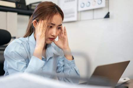 Businesswoman is feeling headache and stressful while reading information in laptop and thoughtful...