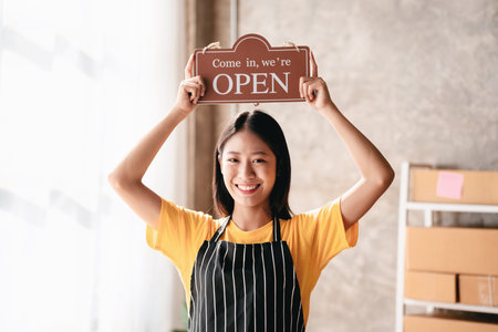 Small business parcel delivery concept, Female entrepreneur putting open sign on head to ready for service shipment delivery for customer while working about shopping online sales business in office.の写真素材